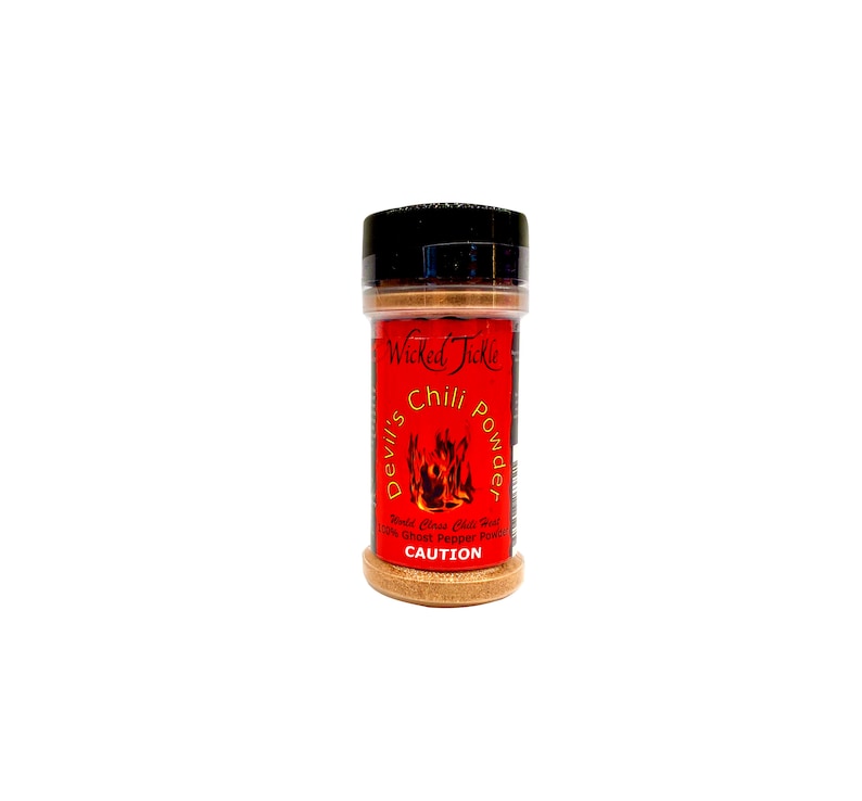 Puede incluir: Un tarro de especias rojo y negro etiquetado como "Wicked Tickle Devil's Chili Powder" con un gr&aacute;fico de llama y el texto "World Class Chili Dust 100% Ghost Pepper Powder CAUTION".