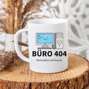 Könnte beinhalten: Weiße Keramik-Tasse mit schwarzem Henkel. Sie zeigt ein Büro-Design mit einem traurigen Computerbildschirm und dem Text "BÜRO 404 Motivation not found."
