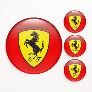 Peut inclure: Plusieurs boutons ronds rouges avec le logo Ferrari. Le logo présente un cheval cabré noir sur un écusson jaune, avec des rayures vertes et rouges en haut, et les lettres "SF" en bas.