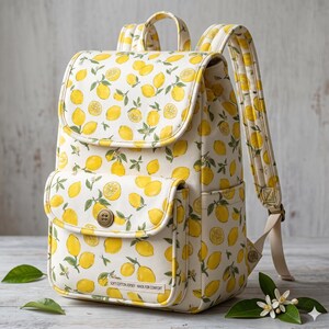 Peut inclure: Un sac &agrave; dos de couleur cr&egrave;me avec un motif r&eacute;p&eacute;titif de citrons jaunes et de feuilles vertes. Le sac poss&egrave;de un rabat sup&eacute;rieur, une poche avant avec une fermeture &agrave; bouton marron et des bretelles r&eacute;glables. Une petite &eacute;tiquette est visible.
