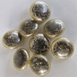 Puede incluir: Ocho cuentas redondas de vidrio transparente con un acabado de purpurina plateada. Las cuentas tienen un diámetro de aproximadamente 2,5 cm.