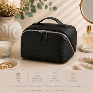May include: A black pebbled leather cosmetic bag with a top handle and silver dual zip fastening. The front is laser engraved with the text Bridesmaid, Aimee, and the date 30.08.2026. The bag features a structured, rounded rectangular shape.