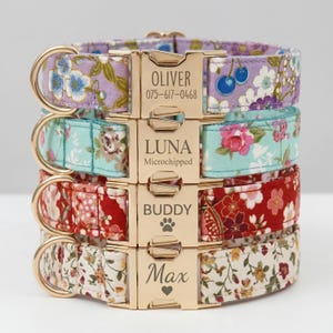 May include: Four stacked dog collars with floral patterns in purple, teal, and red. Each collar has a gold-coloured buckle with a name and contact information or a pet's name engraved. The collars are designed for pets.