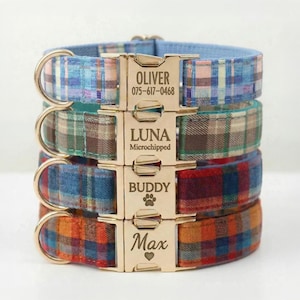 May include: Four plaid dog collars stacked, each with a gold-colored metal buckle. The top collar is blue and white, the second is green and brown, the third is blue and red, and the bottom is orange and blue. Each buckle has a name and phone number or a name and paw print.