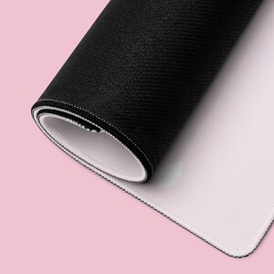 K&ouml;nnte beinhalten: Aufgerollte schwarze Mausunterlage mit strukturierter Oberfl&auml;che und wei&szlig;er Unterseite. Die Kanten sind mit wei&szlig;em Faden gen&auml;ht. Die Mausunterlage befindet sich auf einem rosa Hintergrund.