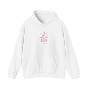 May include: A white hooded sweatshirt featuring a front kangaroo pocket and a drawstring hood. The center chest displays a pink graphic with a disco ball, small stars, and the text "Can I pull you for a chat?" written in a cursive script font.
