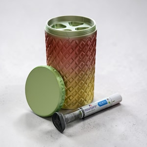 May include: A cylindrical container with a diamond pattern, transitioning from red to yellow. A light green lid sits beside it. A medical injector with the text "mounjaro" is also present.