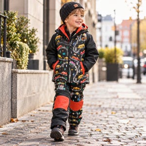 May include: A black hooded winter jacket and matching trousers set featuring a colourful road and vehicle print with red accents. The jacket has a front zip, and the trousers include reinforced red knee patches, worn with a black knit beanie hat.