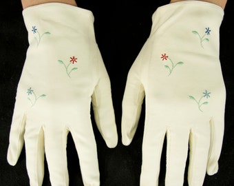 Puede incluir: Un par de guantes de algodón blanco con flores azules y rojas bordadas.