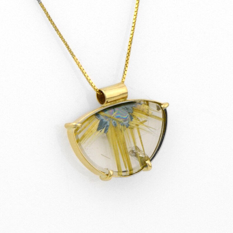 May include: A gold pendant necklace featuring a clear, triangular-shaped stone with gold-colored inclusions. The stone is set in a gold frame and hangs from a delicate gold chain. The pendant has a unique, natural appearance.