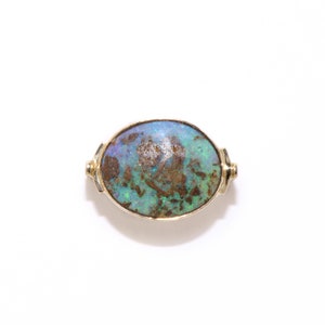 May include: A gold ring with an oval-shaped opal gemstone. The opal has a blue, green, and brown color pattern.