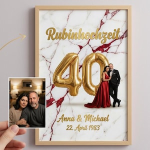 Può includere: Una stampa incorniciata con sfondo marmoreo e testo dorato che recita "Rubinhochzeit" e "40". La stampa include una foto di una coppia e i nomi "Anna & Michael" con la data "22. April 1983". Una piccola foto di una coppia è tenuta davanti alla stampa.