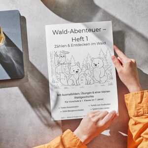 Könnte beinhalten: Eine Person hält ein gedrucktes Aktivitätsbuch mit dem Titel "Wald-Abenteuer - Heft 1" mit Illustrationen von Waldtieren. Das Buch ist für Vorschulkinder und Erstklässler konzipiert und enthält Ausmalbilder und Übungen.