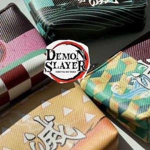 May include: Close-up of five small, rectangular pouches with various patterns and colours. The pouches feature designs like checkered patterns, geometric shapes, and Japanese text. The Demon Slayer logo is in the centre.