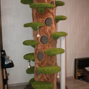 May include: A tall cat tree designed to resemble a tree trunk. It has a brown, textured surface with several green, leaf-shaped platforms. The structure includes circular openings, a white scratching post, and a brown base.