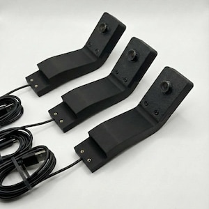 May include: Three black, angled devices with attached cables and USB connectors. Each device has a small, circular lens on the top angled section. The devices are arranged on a white surface.