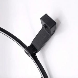 May include: A black, curved lamp with a white light strip. The lamp has a rectangular base and a connecting arm. The lamp is set against a white background.