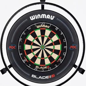 May include: A Winmau Blade 6 dartboard with a black surround and integrated lighting. The dartboard has a traditional design with red, green, and black segments. The Winmau logo is visible at the top of the board.