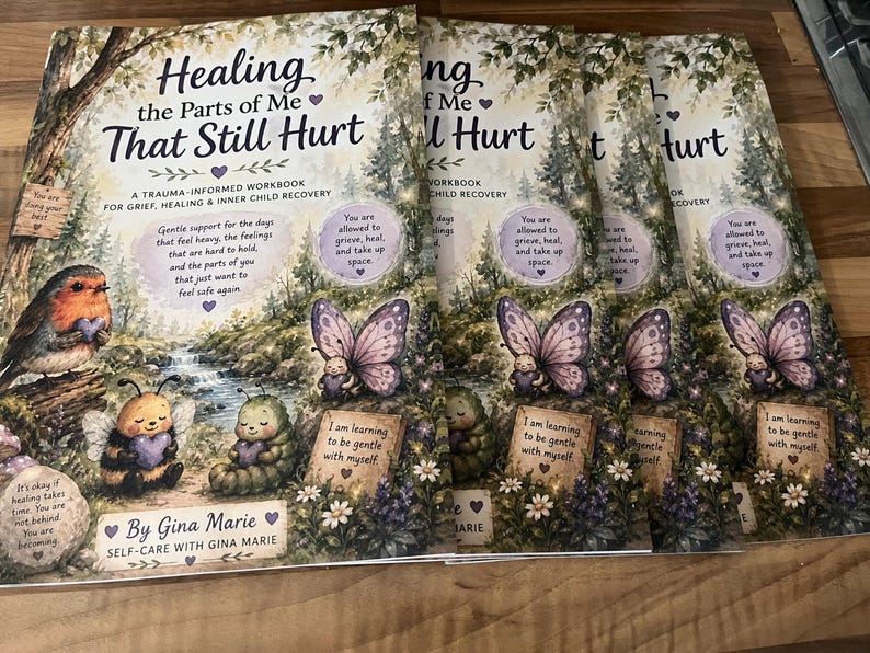 May include: A stack of identical workbooks titled Healing the Parts of Me That Still Hurt by Gina Marie. The cover features a robin, a bee, and a caterpillar in a forest setting with butterflies and text about trauma, grief, and inner child recovery.