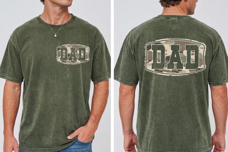 May include: Olive green t-shirt with the word "DAD" in a camouflage design on the front and back. The shirt has a crew neck and short sleeves. The fabric appears to be a soft, washed cotton.