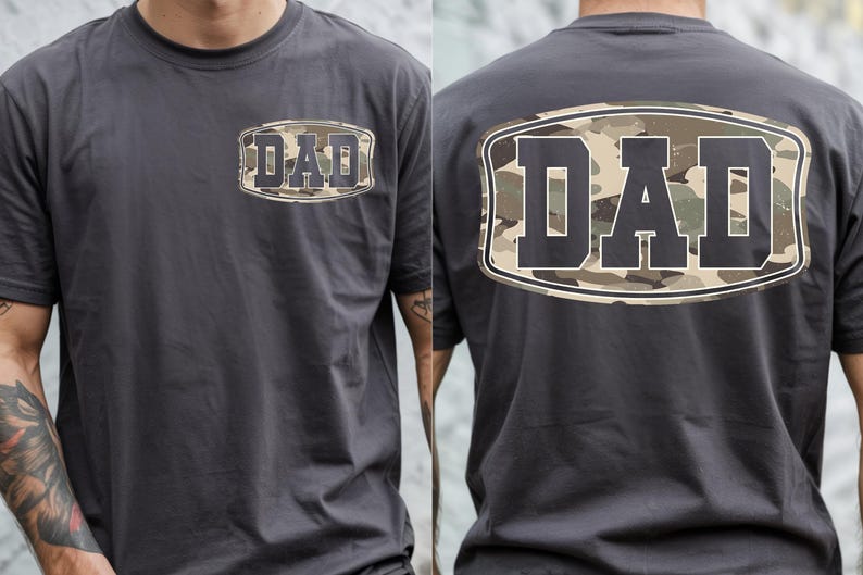 May include: Charcoal gray t-shirt with the word "DAD" in a camouflage design on the front and back. The text is inside a white and black oval. The shirt is short-sleeved and made of a soft material.