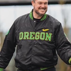 May include: Black satin jacket with the word "OREGON" in green and yellow lettering. The jacket has green and yellow striped trim on the collar, cuffs, and waist. A yellow Nike swoosh is visible.