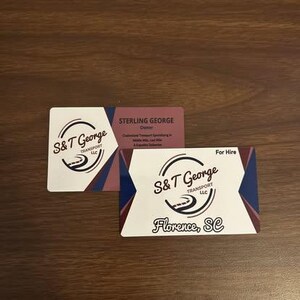 May include: Two business cards with the S&T George Transport LLC logo. One card is white with a burgundy and navy blue design. The other card is burgundy with white text. The words "Florence, SC" are visible.