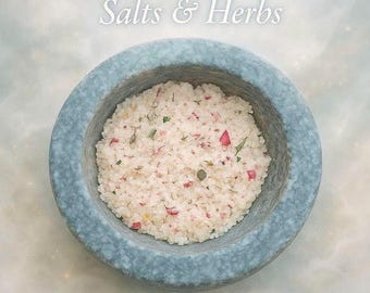 May include: A round, blue-grey stone bowl filled with white bath salts and herbs. The salts are speckled with pink rose petals and green herbs. Text at the top reads "Magical Ritual Bath Salts & Herbs". The Occult Shop UK is at the bottom.
