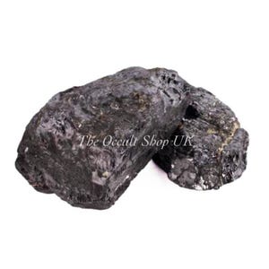 May include: Two rough, dark gray tourmaline stones. The stones have a textured surface and are displayed against a white background. The text "The Occult Shop UK" is visible on the image.