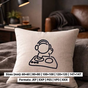 May include: Cream-coloured square cushion featuring a black embroidered astronaut DJ design. The cushion is on a bed, with a brown leather chair in the background. Text on the image indicates available sizes and embroidery formats.