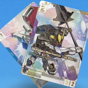 May include: Two trading cards featuring Gundam robots. The front card displays "Gundam Barbatos 1st Form" with a detailed illustration of the robot. The cards have a blue and purple color scheme with Japanese text.