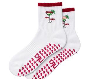 May include: A pair of white crew socks with a dark red ribbed cuff. Each sock features an embroidered margarita glass with a lime slice and the text "extra spicy" in red. The soles have pink rubberized grip dots and the brand name "pnu".