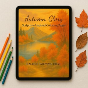May include: A digital tablet displays a landscape illustration with the text "Autumn Glory Scripture-Inspired Coloring Pages." The image features a lake, mountains, and trees in autumn colors. Colored pencils and fall leaves are arranged around the tablet.