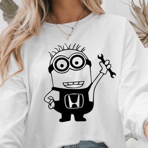 May include: White long-sleeved sweatshirt with a black and white cartoon minion holding a wrench. The minion is wearing a black jumpsuit with the Honda logo. The design is a fun take on automotive themes.