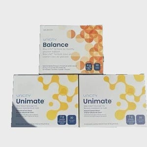 May include: Three rectangular boxes of Unicity dietary supplements. The top box is labeled Balance with orange circular patterns, weighing 217.5 g (7.5 oz). The two bottom boxes are labeled Unimate with yellow molecular patterns, weighing 153 g (5.4 oz).
