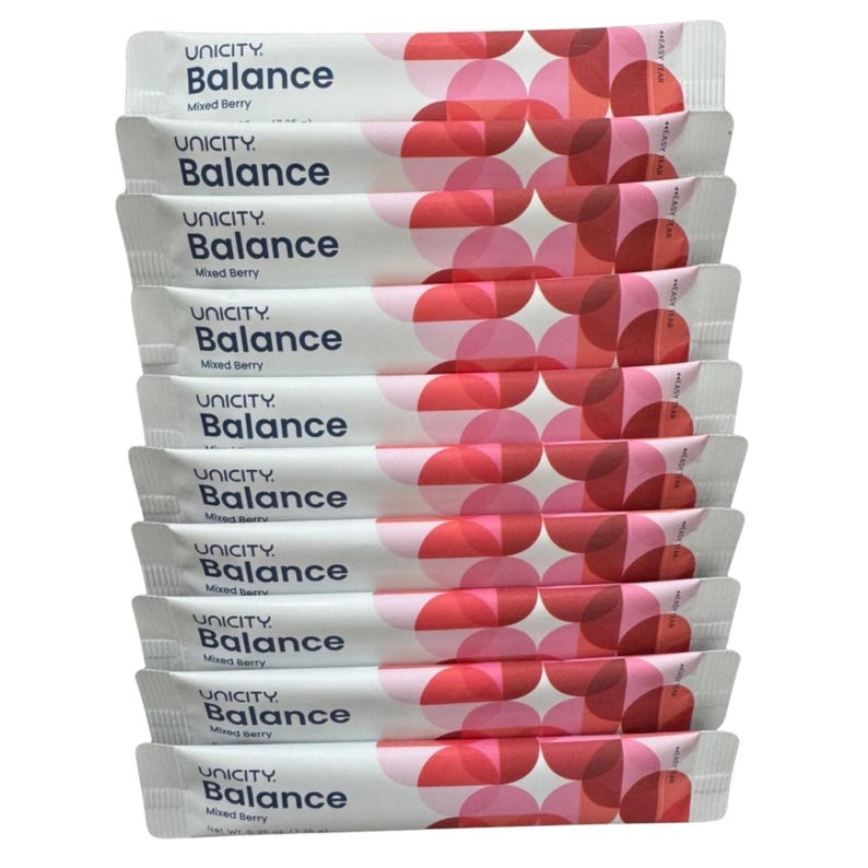 May include: A stack of ten white Unicity Balance Mixed Berry supplement packets. Each individual packet features the brand name Unicity, the product name Balance, and the flavour Mixed Berry in dark blue text, alongside a geometric pattern of pink and red circles.