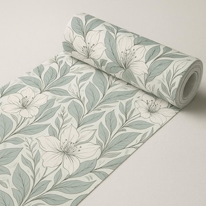 Puede incluir: Un rollo de papel pintado con un diseño floral. El diseño presenta grandes flores blancas con contornos grises y hojas verde grisáceo sobre un fondo claro. El rollo está parcialmente desenrollado, revelando el patrón.