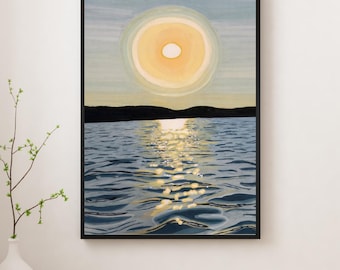 May include: A framed art print depicting a sunset over water. The sun is a large, yellow circle with a white center, reflecting on the water's surface. The water is blue with light reflections, and a dark land mass is visible in the distance.
