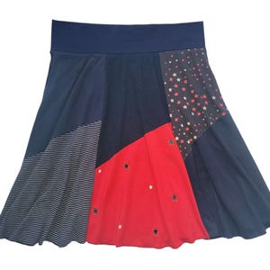 Könnte beinhalten: A-Linien-Rock mit marineblauem Bund und Patchwork-Design. Der Rock hat Stoffbahnen in Marineblau, Rot und Streifen, mit Sternen. Das rote Feld hat goldene Sternverzierungen, und das marineblaue Feld hat rote und weiße Sterne.
