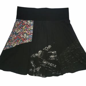 May include: Black skirt with a wide black waistband and a flared silhouette. Features a floral print panel and a graphic print with the word "Cycle". The skirt has a unique, patchwork design.