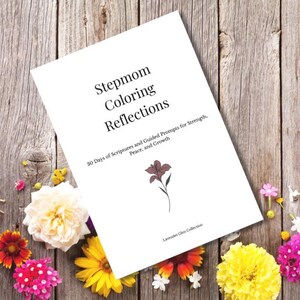 May include: A white book titled "Stepmom Coloring Reflections" with text and a floral illustration. The book is surrounded by colorful flowers on a wooden background. The book's subtitle reads "30 Days of Scriptures and Guided Prompts for Strength, Peace, and Growth."