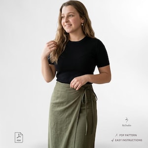 May include: A woman in a black short-sleeved top and an olive green wrap skirt tied at the waist. The image includes the text "By Dadin", "PDF Pattern", and "Easy Instructions".