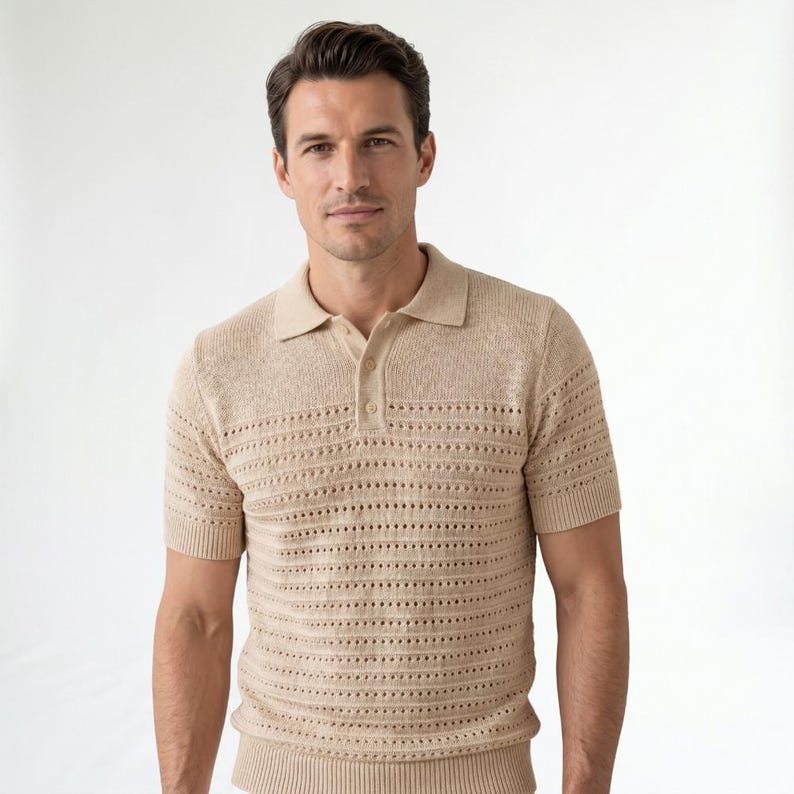 May include: A short-sleeved polo shirt in a light beige color, featuring a textured knit fabric with horizontal rows of openwork detailing. The shirt has a classic collar, a buttoned placket with two visible buttons, and ribbed cuffs and hem.