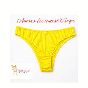 Puede incluir: Tanga amarillo brillante con un pequeño lazo en la parte delantera. El texto "Amara Essential Tanga" está escrito en cursiva roja encima de la ropa interior. El logotipo de "Virtuosa's Intimates" está en la esquina inferior izquierda.
