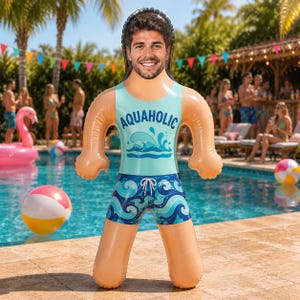 Puede incluir: Un flotador inflable con forma de persona y un rostro personalizado. La figura lleva una camiseta sin mangas azul claro con el texto AQUAHOLIC y un gráfico de olas, junto con un bañador azul con un patrón de olas blancas y un cordón.