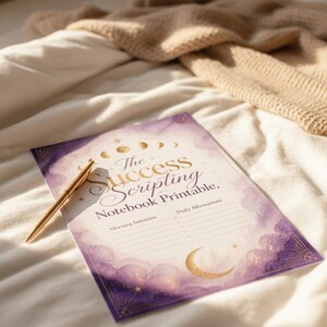 a notebook with a pen resting on top of it, placed on a bed with a blanket.
