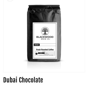 Puede incluir: Una bolsa negra de café Blackwood Brew Co. La etiqueta dice "Fresh Roasted Coffee" y presenta un logotipo de árbol. La bolsa está etiquetada como "Dubai Chocolate".
