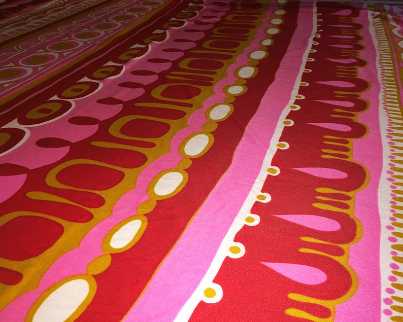 May include: Abstract patterned fabric with a repeating design of red, pink, white, and gold circles, ovals, and teardrop shapes.