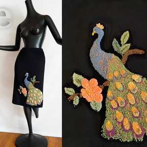 Puede incluir: Una falda negra con un pavo real bordado en el lateral. El pavo real está hecho de hilo de colores y tiene una cola verde, azul y amarilla.