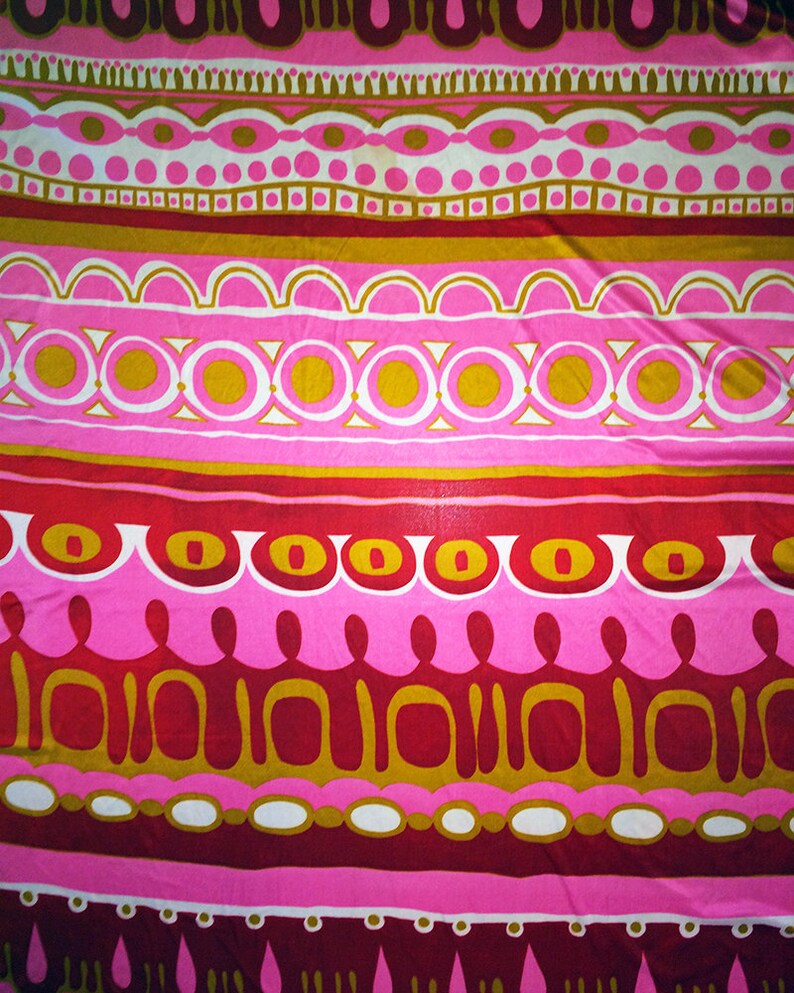 May include: A pink and red fabric with a repeating geometric pattern of circles, ovals, and arches. The pattern is in shades of pink, red, gold, and white.
